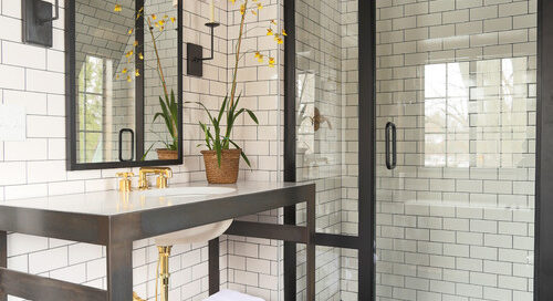 Elegant bathroom featuring subway tiles, a glass shower, and a wooden vanity with gold fixtures. Designed by Pratt Home Builders in Chattanooga TN.