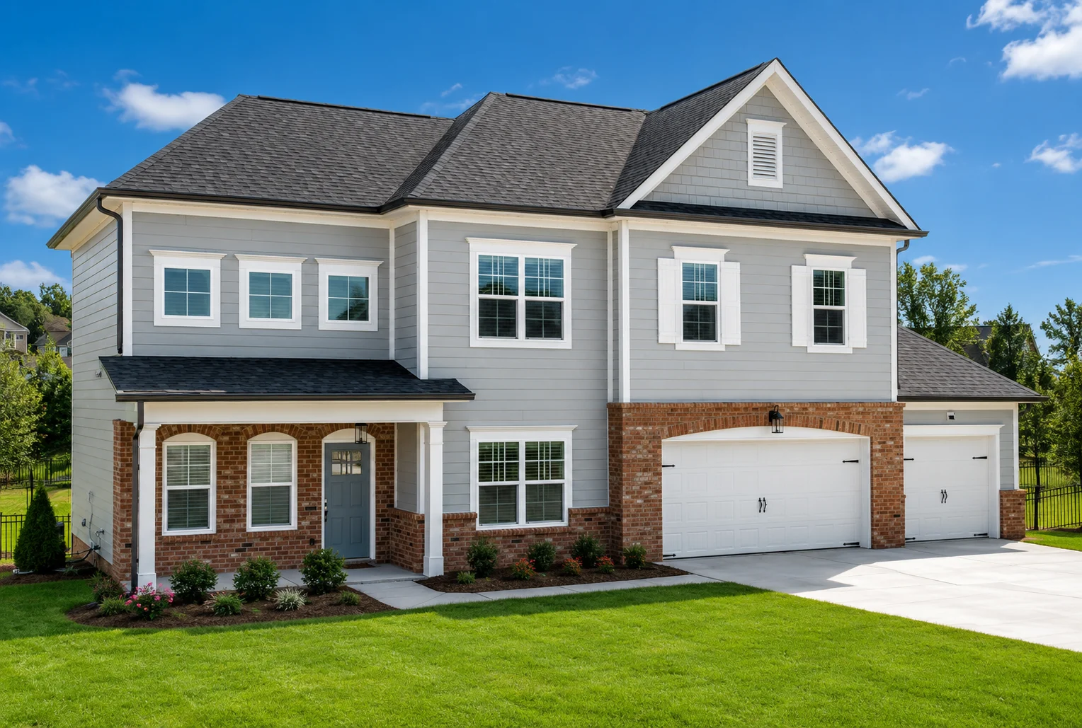 Hudson-floor-plan-front-exterior-home-for-sale Two-story home with gray siding, brick accents, and a double garage by Pratt Home Builders in Chattanooga TN, set in a green lawn under blue sky.