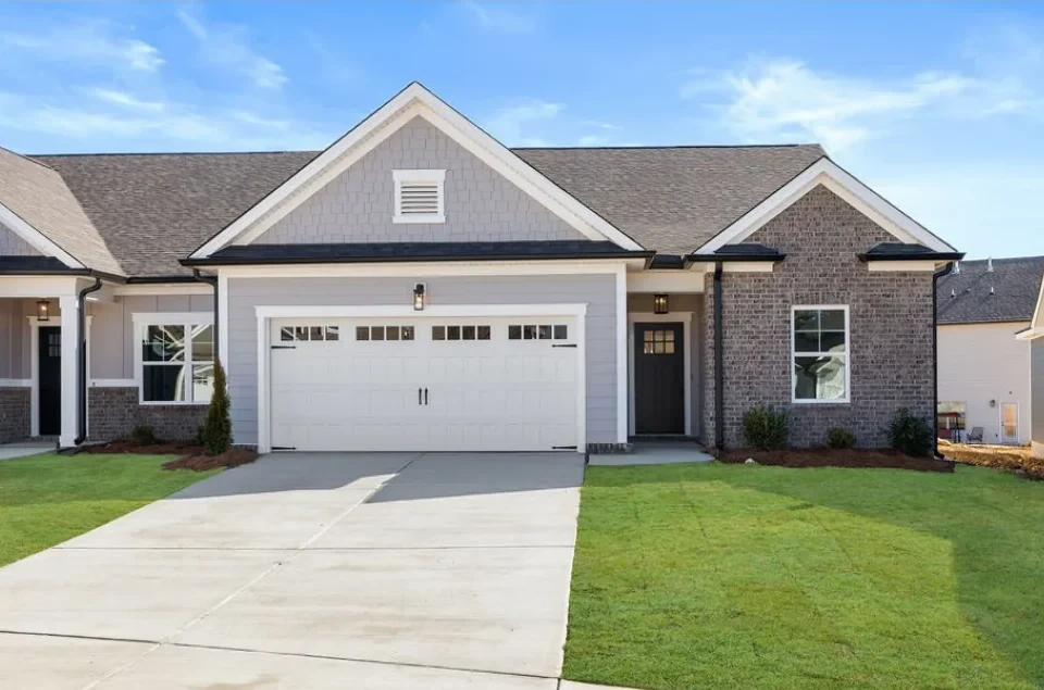 Lily-plan-exterior-front-east-brainerd New Home Chattanooga TN. Modern single-story brick home with a two-car garage, fresh lawn, built by Pratt Home Builders under clear blue skies.