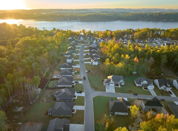 New Homes Chattanooga TN Aerial view of a serene Soddy Daisy community by a lake, surrounded by lush trees, built by Pratt Home Builders in Chattanooga TN at sunrise.