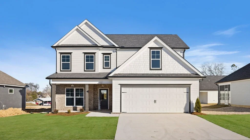 Two-story modern house with a large garage and green lawn, built by Pratt Home Builders in Chattanooga, TN, under a clear blue sky.