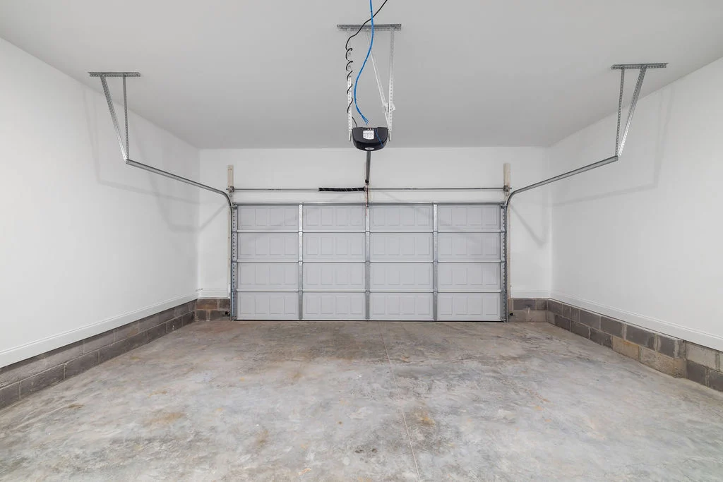New Home Chattanooga TN. Empty garage with concrete floor and automatic door system, designed by Pratt Home Builders.