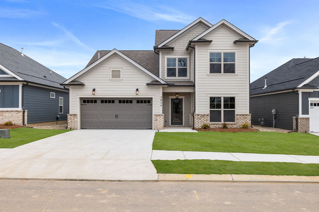 Modern two-story house with a gray facade and garage, built by Pratt Home Builders in Chattanooga TN, surrounded by freshly landscaped lawn.