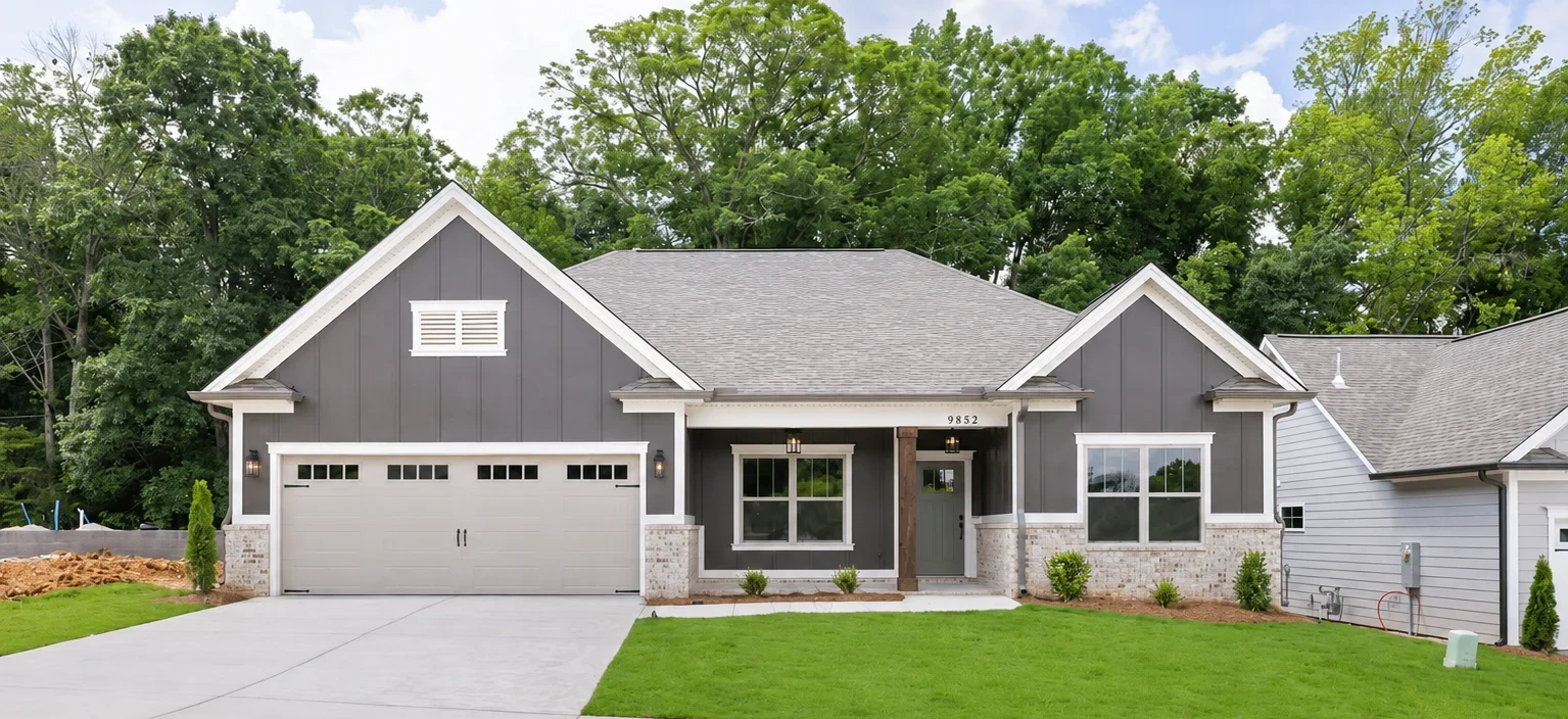 Modern gray and white home with a two-car garage, manicured lawn, and trees in the background, built by Pratt Home Builders in Chattanooga TN.