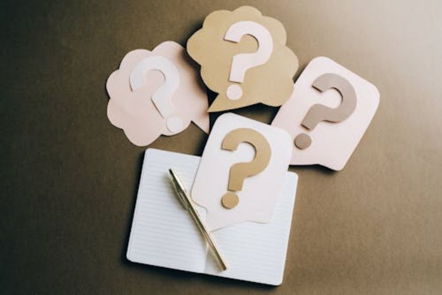 Notebook and pen with speech bubbles featuring question marks, symbolizing queries. Relevant for Pratt Home Builders in Chattanooga TN context.