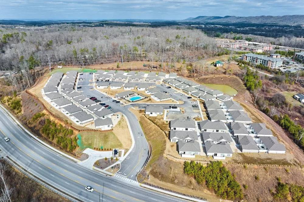Aerial view of residential development by Pratt Home Builders in Chattanooga TN, with houses and a central pool, surrounded by wooded areas.