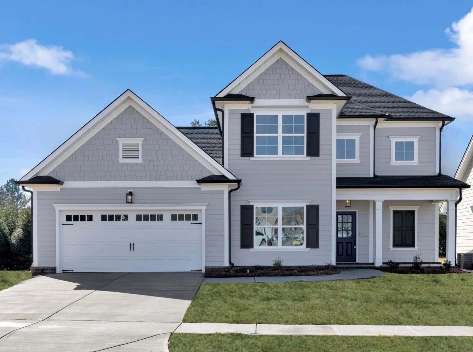 New Home Chattanooga TN. Two-story gray house with white trim, black shutters, and a double garage. Built by Pratt Home Builders. Clear blue sky above.