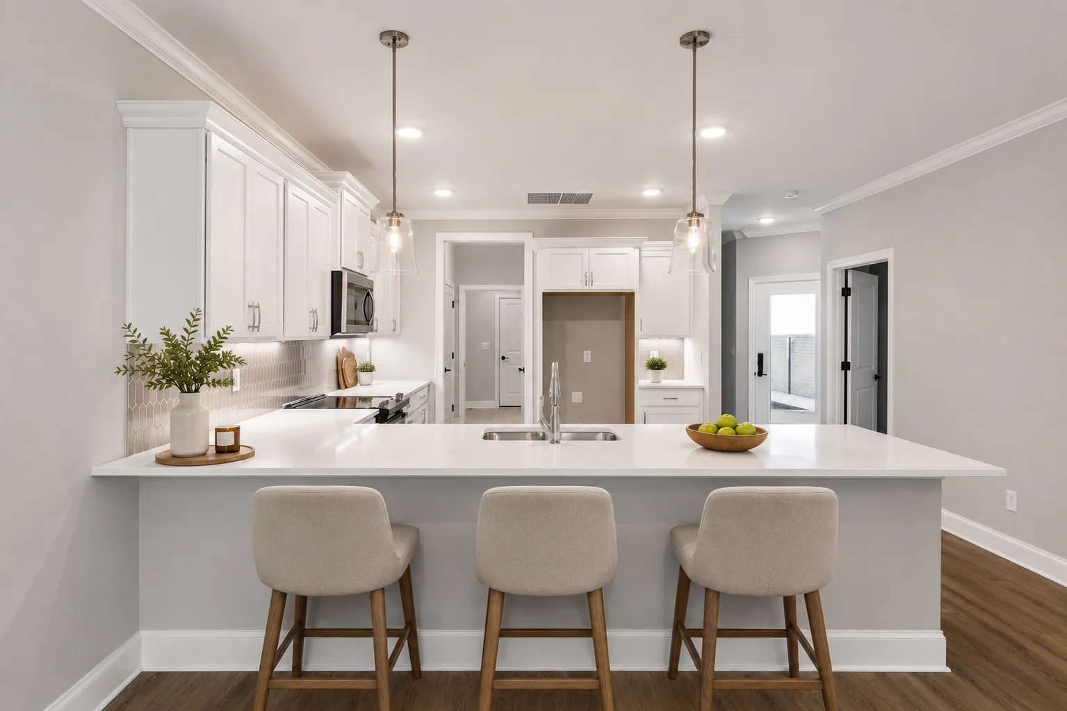 Modern kitchen with white cabinetry, pendant lights, island seating, and stainless appliances, designed by Pratt Home Builders in Chattanooga TN.
