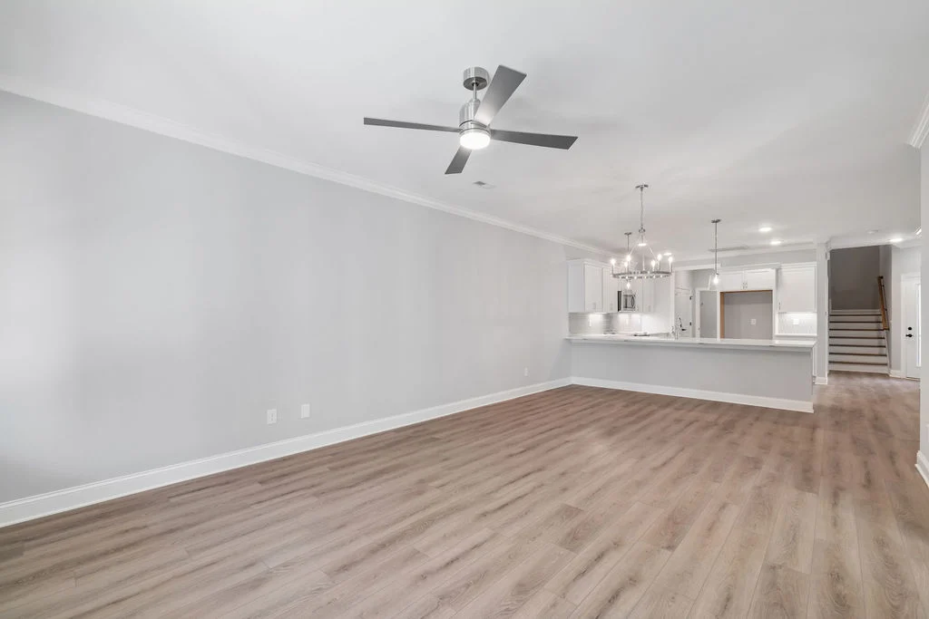 New Home Chattanooga TN. Spacious open-concept living area with wood floors, ceiling fan, modern kitchen, and hanging lights by Pratt Home Builders.