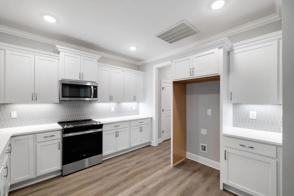 New Home Chattanooga TN. Modern kitchen with white cabinets, stainless steel appliances, hexagonal backsplash, and wood flooring by Pratt Home Builders.