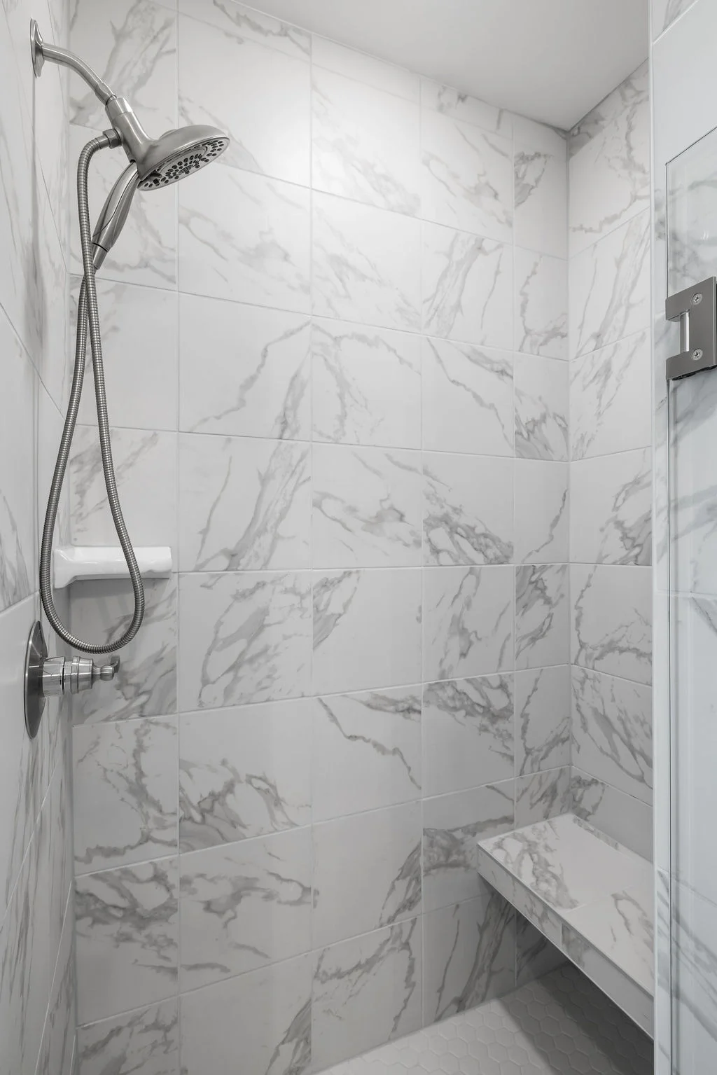 New Home Chattanooga TN. Modern shower with marble-patterned tiles, bench, and adjustable showerhead, designed by Pratt Home Builders.