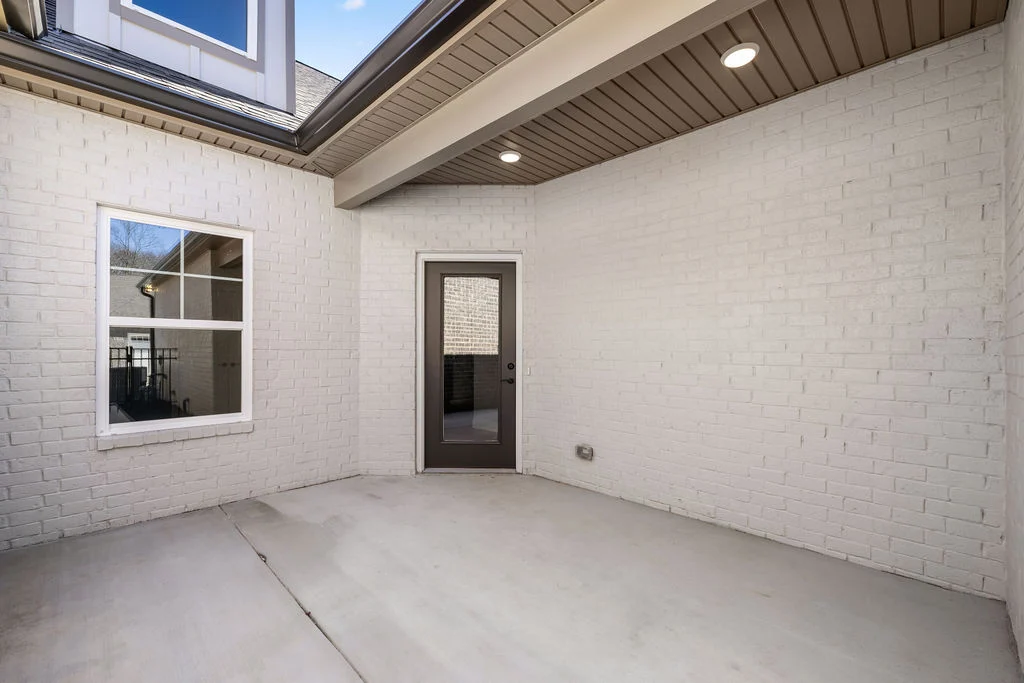 New Home Chattanooga TN. Spacious patio with white brick walls and a glass door, designed by Pratt Home Builders.