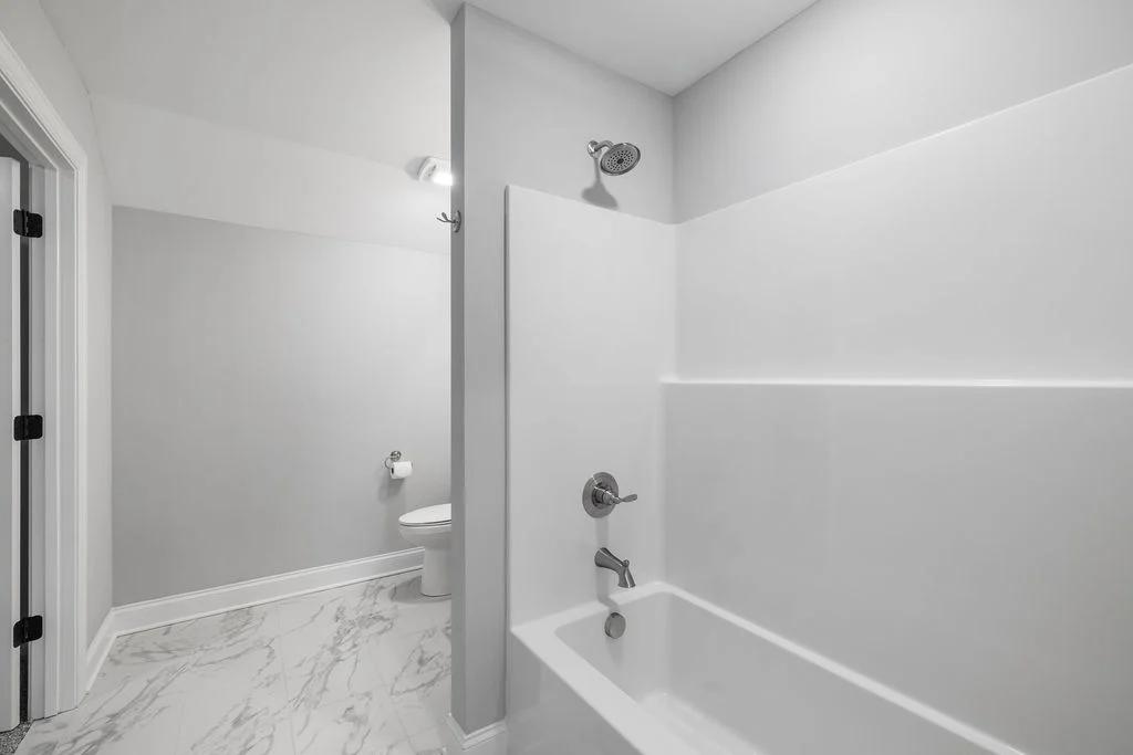 Modern bathroom with white bathtub, sleek fixtures, and marble-patterned floor. Designed by Pratt Home Builders in Chattanooga TN.