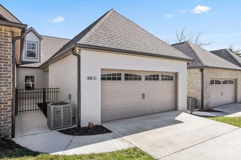 Single-story home with white brick exterior, gabled roof, and beige garage door by Pratt Home Builders in Chattanooga, TN.