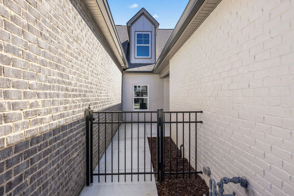 Pathway between brick walls with a black metal gate and window. Pratt Home Builders in Chattanooga TN.