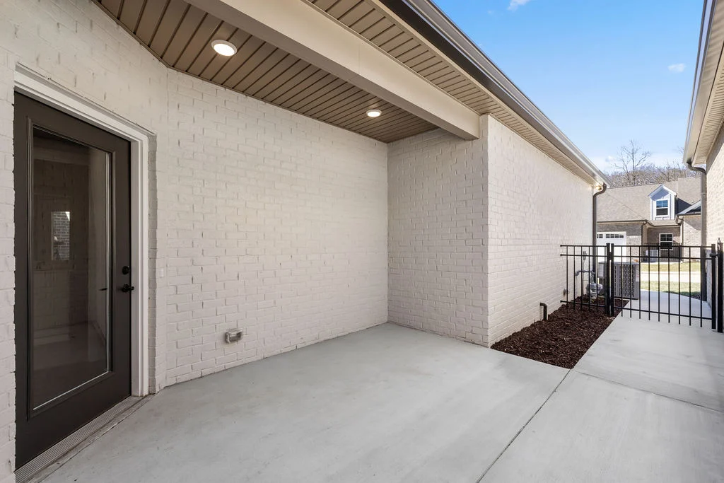Covered patio with white brick walls and a glass door, designed by Pratt Home Builders in Chattanooga, TN.