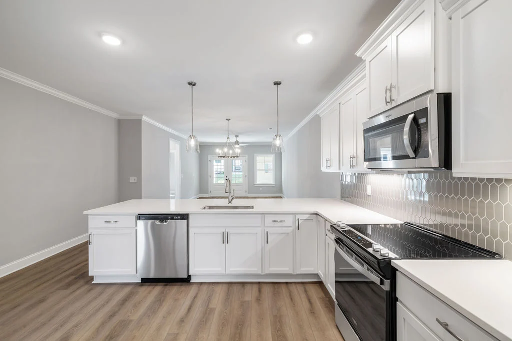Modern kitchen with white cabinetry, stainless steel appliances, hexagonal tile backsplash, and pendant lighting by Pratt Home Builders in Chattanooga