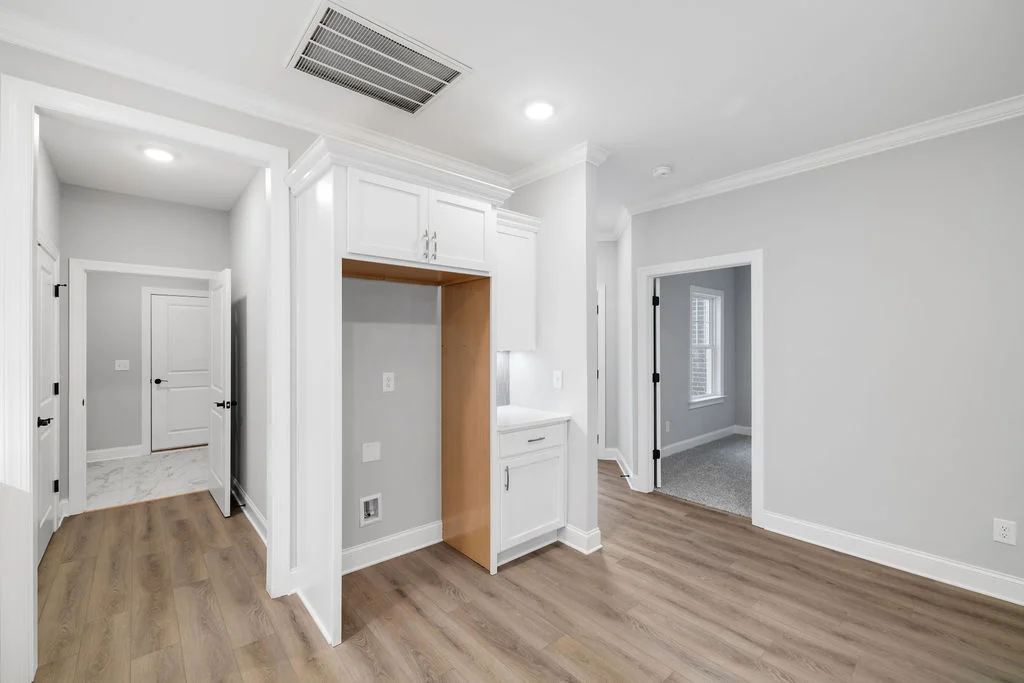 Modern interior with light wood flooring, white cabinetry, and gray walls, designed by Pratt Home Builders in Chattanooga TN.