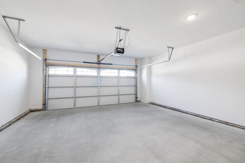 Spacious, well-lit garage with white walls and a closed garage door, designed by Pratt Home Builders in Chattanooga TN.