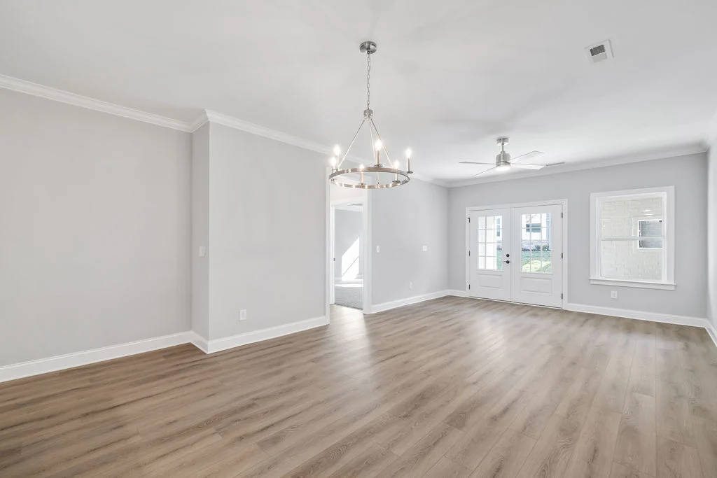 Spacious, bright room with hardwood floors, chandelier, ceiling fan, and double doors by Pratt Home Builders in Chattanooga TN.