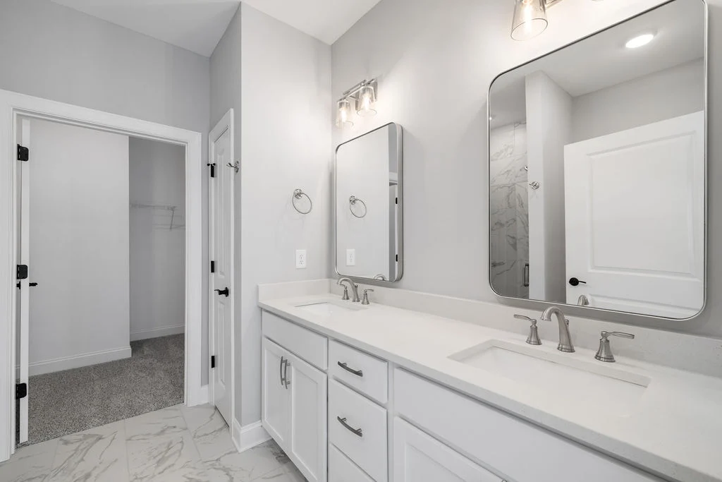 Modern bathroom by Pratt Home Builders in Chattanooga TN, featuring double vanity, large mirrors, marble floor, and elegant lighting.