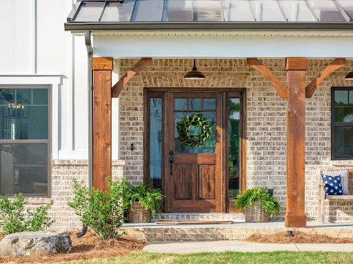Pratt New Home Chattanooga TN Charming porch with rustic wooden door and columns, decorated with a wreath and plants. Built by Pratt Home Builders in Chattanooga TN.