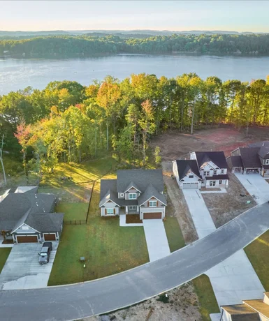 Built for Long-Term Value Aerial view of modern homes by a lake, surrounded by trees, built by Pratt Home Builders in Chattanooga TN, showcasing scenic neighborhood layout.
