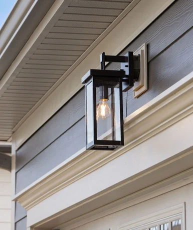 Built with Better Materials Outdoor lantern sconce on a modern home's exterior by Pratt Home Builders in Chattanooga TN, featuring a black frame and suspended bulb.