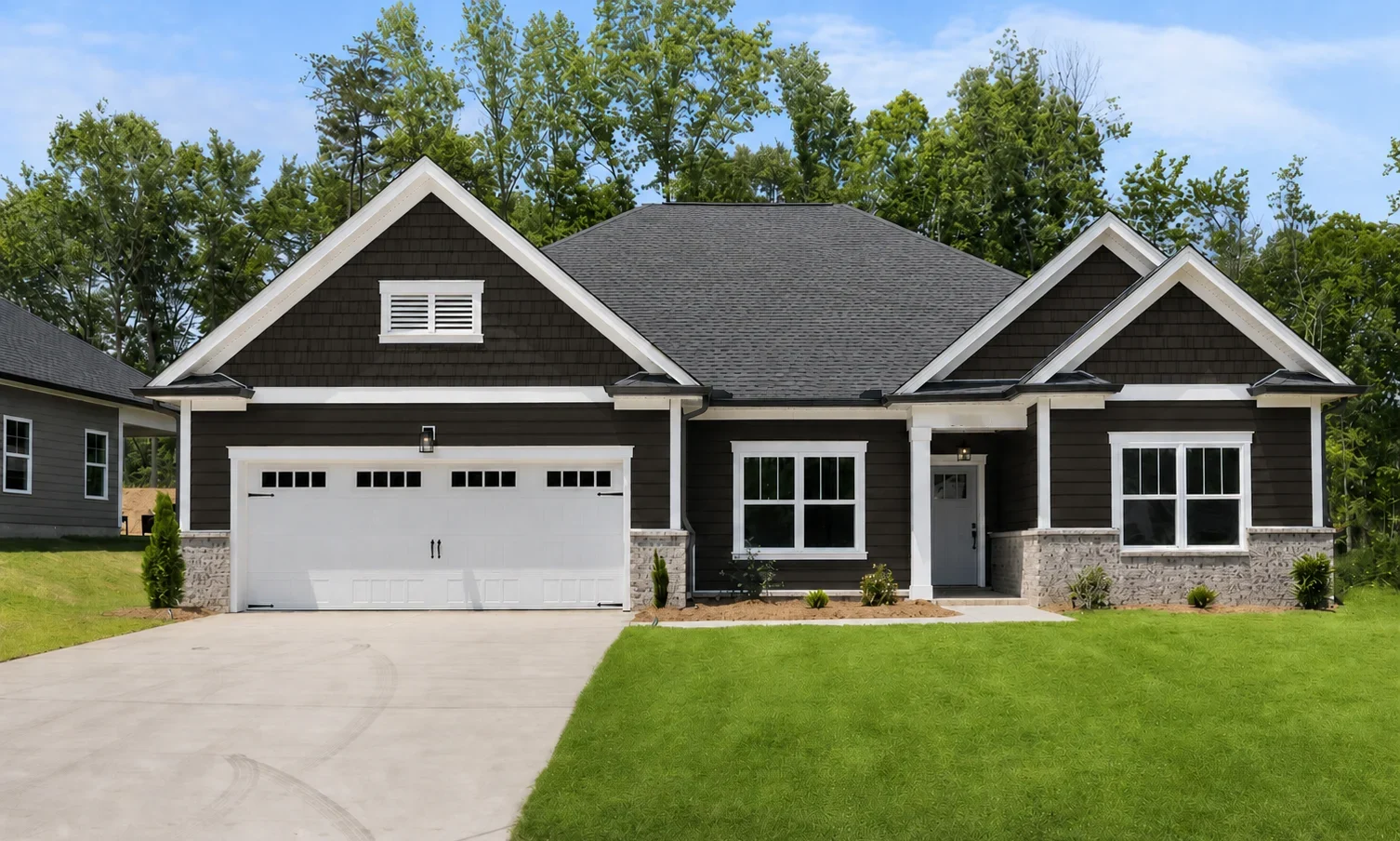 Single-story home by Pratt Home Builders in Chattanooga TN, featuring a dark facade, two-car garage, and manicured lawn, set against lush trees.