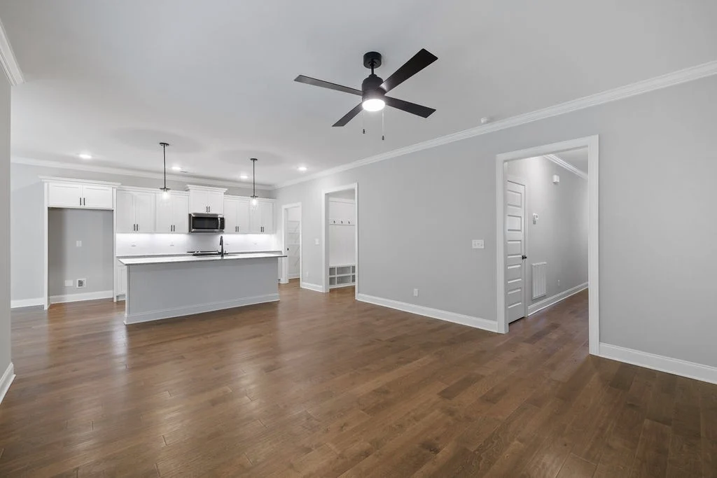 Spacious open-concept kitchen and living area with wood floors, ceiling fan, white cabinetry, and island by Pratt Home Builders in Chattanooga TN.