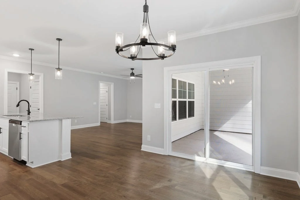 Open-concept living space with hardwood floors, modern chandeliers, and sliding glass doors by Pratt Home Builders in Chattanooga TN.