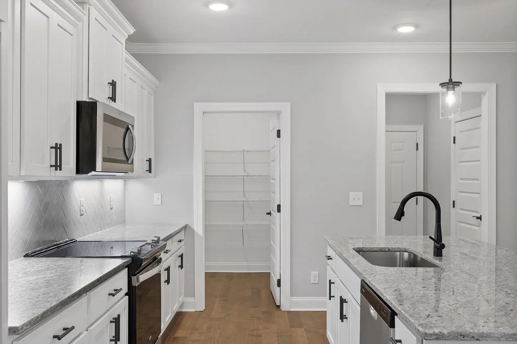 Modern kitchen featuring white cabinets, granite countertops, and stainless steel appliances. Designed by Pratt Home Builders in Chattanooga TN.