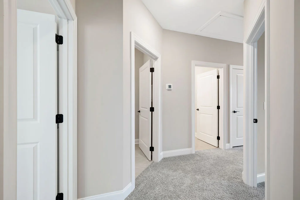 Carpeted hallway with multiple white doors, created by Pratt Home Builders in Chattanooga TN.