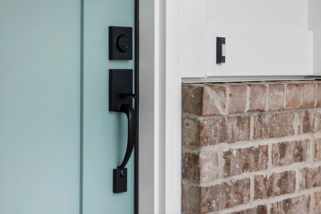 Turquoise door with black handle, alongside a brick wall, designed by Pratt Home Builders in Chattanooga TN.