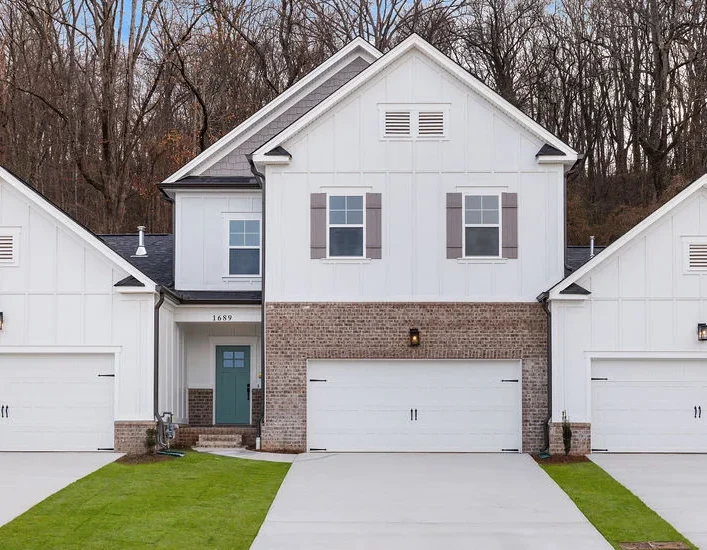 Modern white duplex with three garages, brick accents, and manicured lawns by Pratt Home Builders in Chattanooga TN.