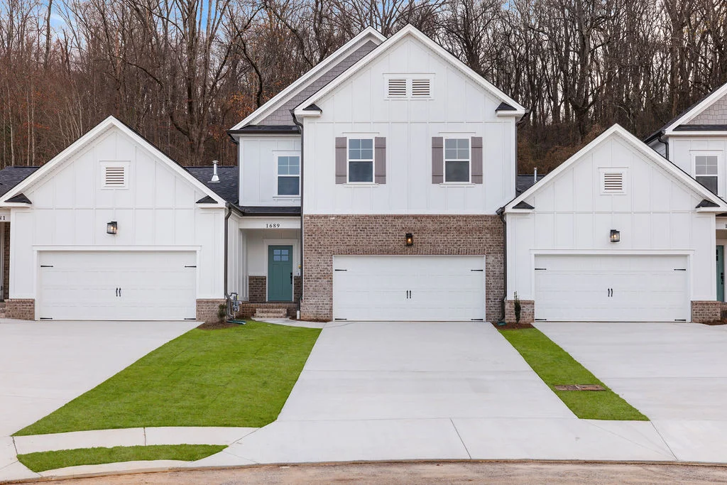 Modern white duplex with three garages, brick accents, and manicured lawns by Pratt Home Builders in Chattanooga TN.