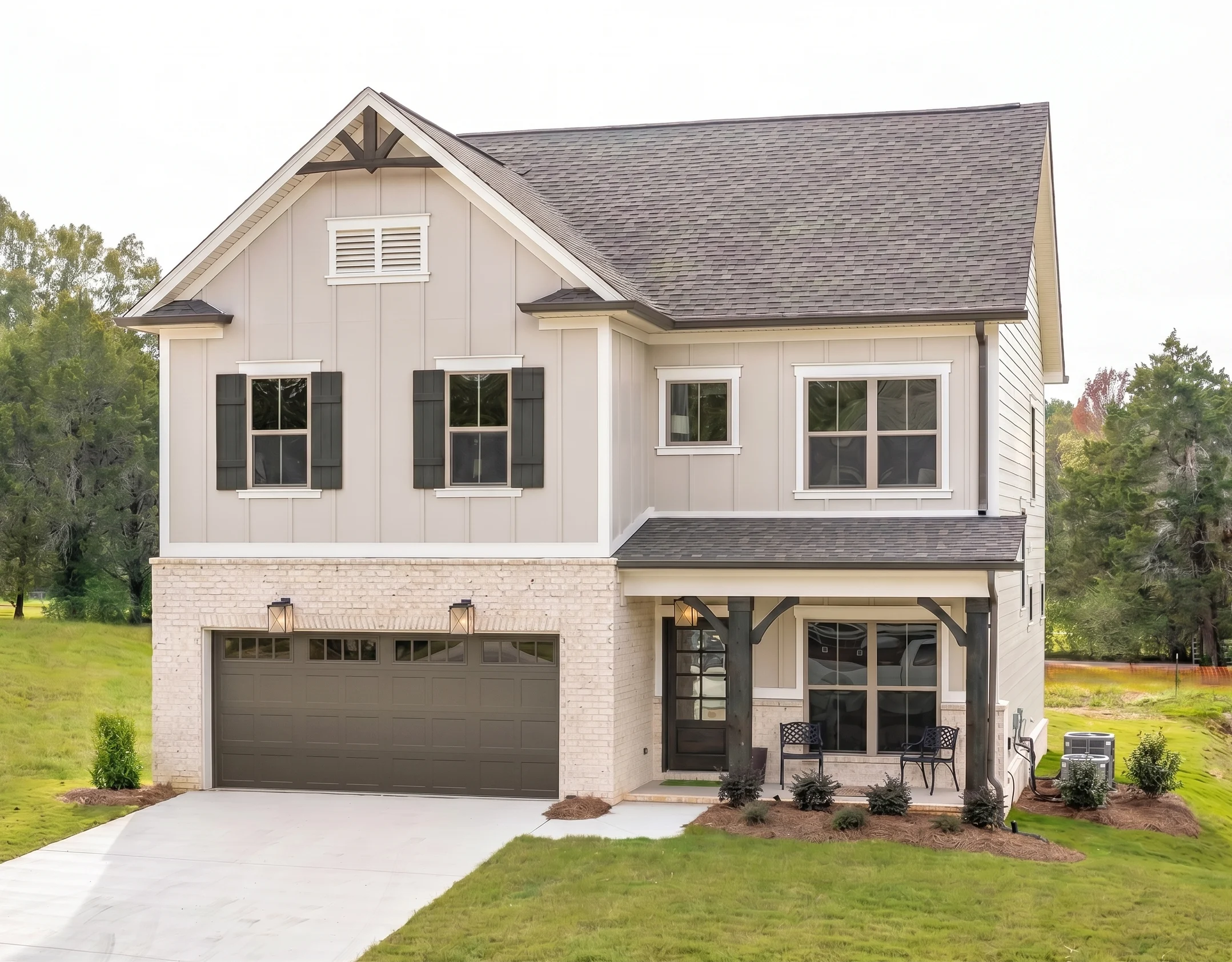 Two-story house with gray siding, dark shutters, and a front porch. Built by Pratt Home Builders in Chattanooga TN, surrounded by greenery.