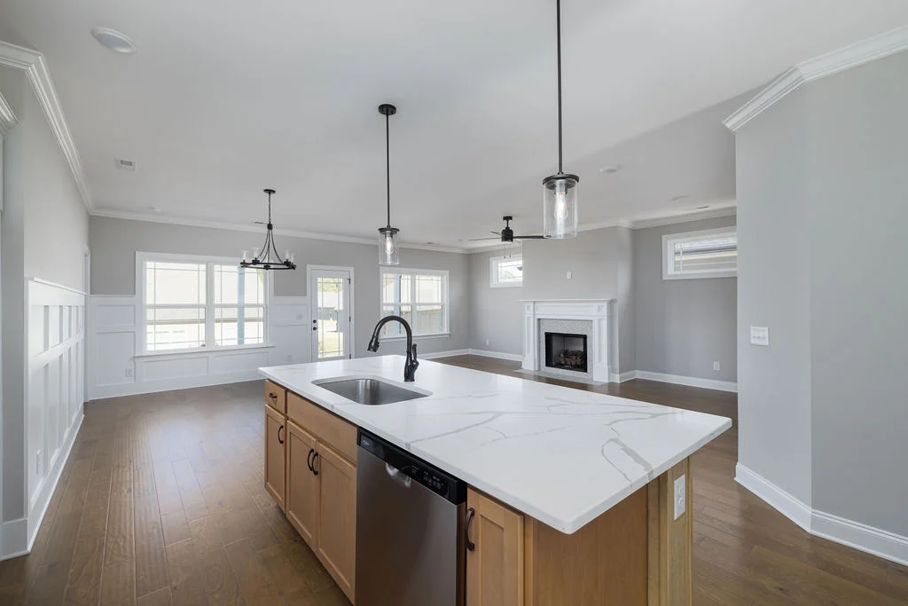 Spacious modern kitchen and living area by Pratt Home Builders in Chattanooga TN, featuring marble island, hardwood floors, and fireplace.