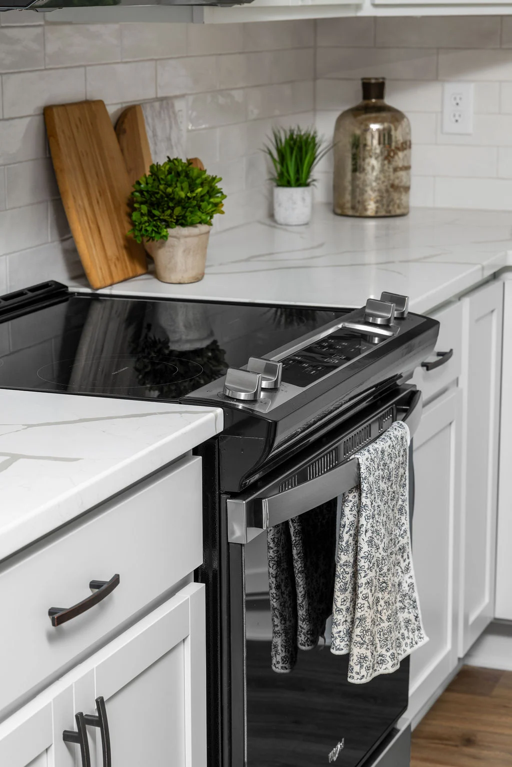 Modern kitchen with black stovetop, white cabinets, and decorative plants. Designed by Pratt Home Builders in Chattanooga TN.
