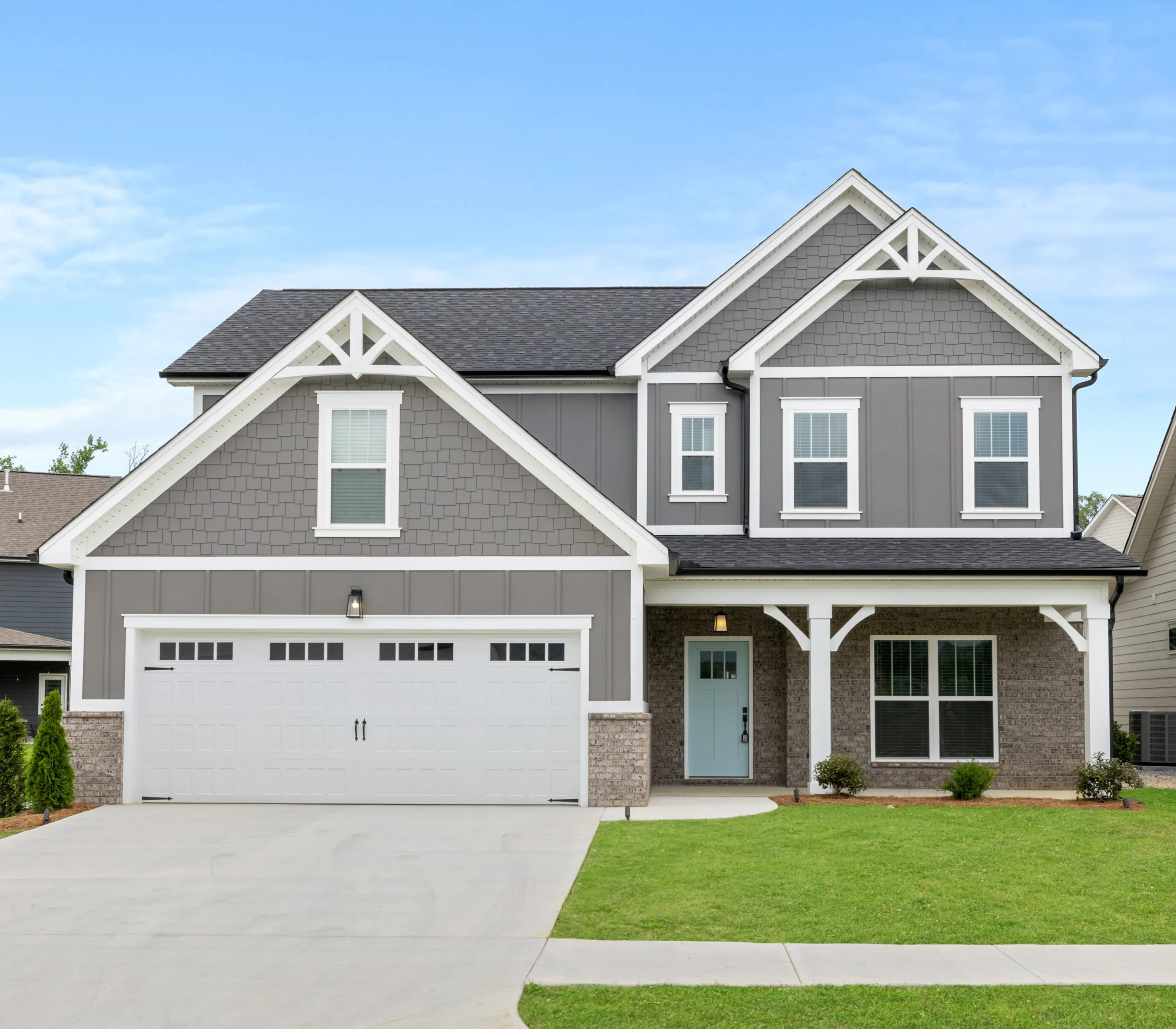 Modern two-story gray house with white trim, large garage, and manicured lawn by Pratt Home Builders in Chattanooga TN.