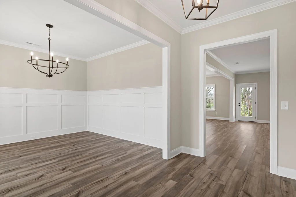 Spacious, light-filled room with elegant chandeliers, wainscoting, and hardwood floors. Built by Pratt Home Builders in Chattanooga TN.