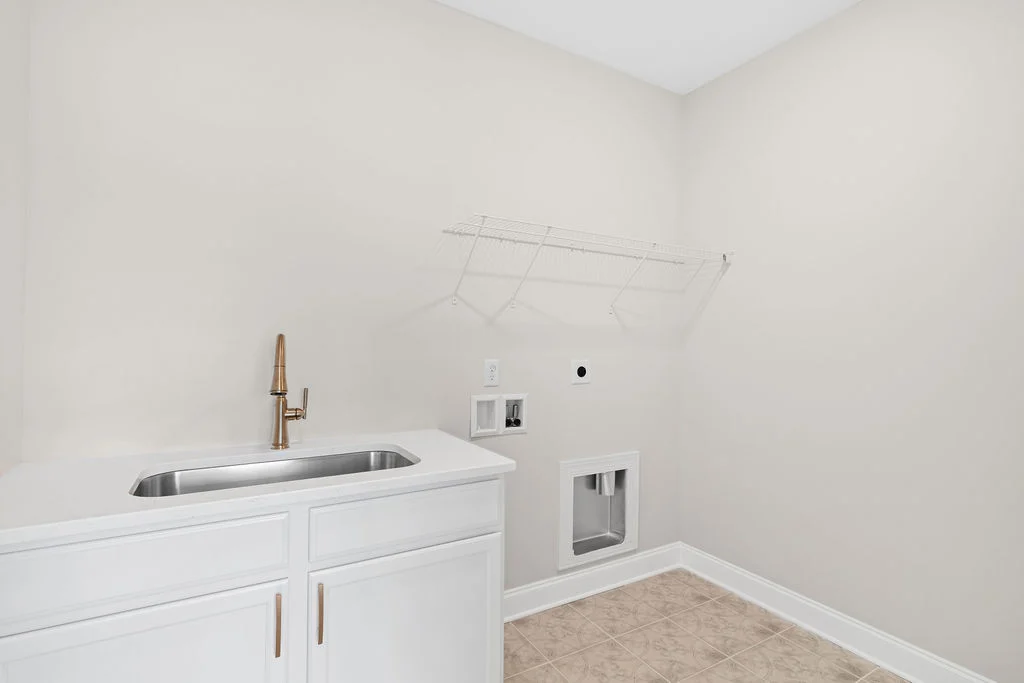 Laundry room with white cabinets, stainless steel sink, and metal shelf. Washer and dryer hookups. Built by Pratt Home Builders in Chattanooga TN.