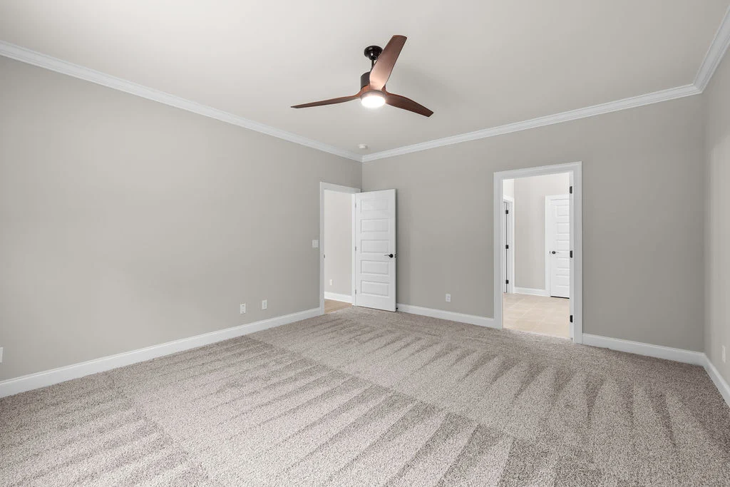 Spacious carpeted room with beige walls, ceiling fan, and open doors by Pratt Home Builders in Chattanooga TN.
