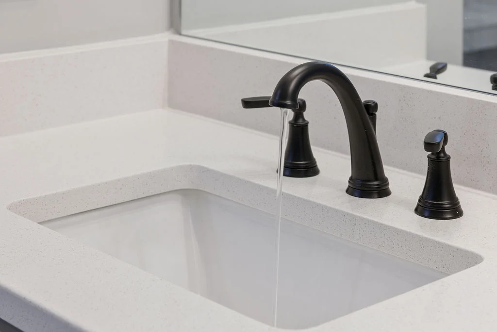 Elegant black faucet with water running, set in a white countertop by Pratt Home Builders in Chattanooga TN.