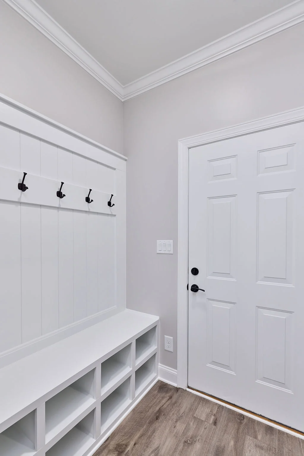 White mudroom with hooks, bench, and cubbies, featuring a modern door, showcasing design by Pratt Home Builders in Chattanooga TN.