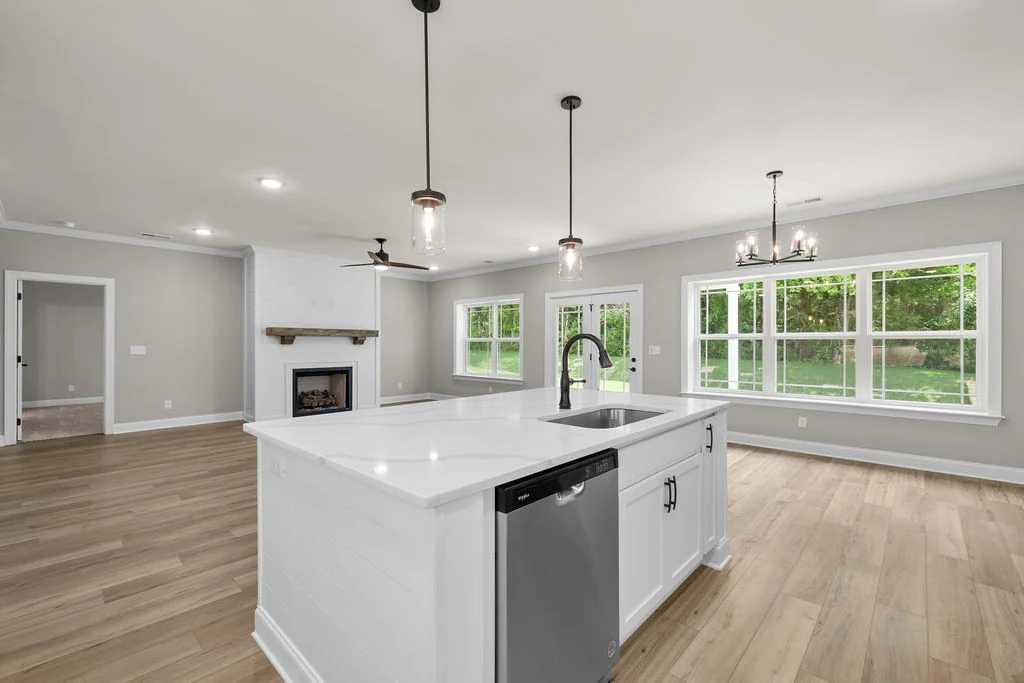 Spacious modern kitchen and living area by Pratt Home Builders in Chattanooga, TN, featuring large windows, island sink, and hardwood floors.