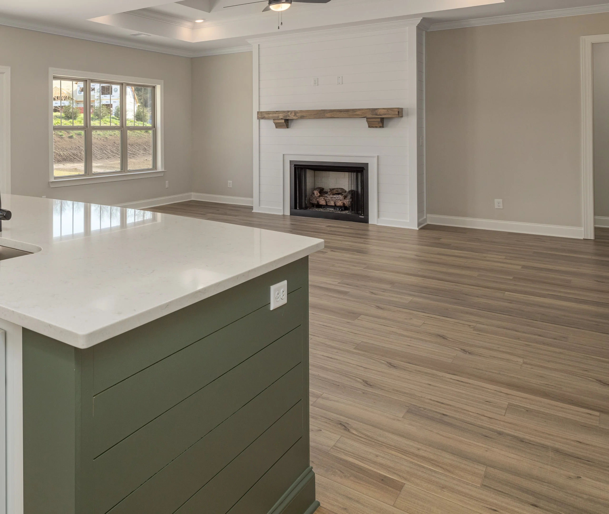Spacious living area with wood floors, shiplap fireplace, marble island; built by Pratt Home Builders in Chattanooga, TN.