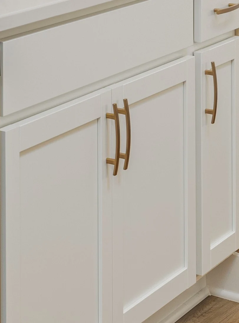 White kitchen cabinets with sleek gold handles, crafted by Pratt Home Builders in Chattanooga TN.